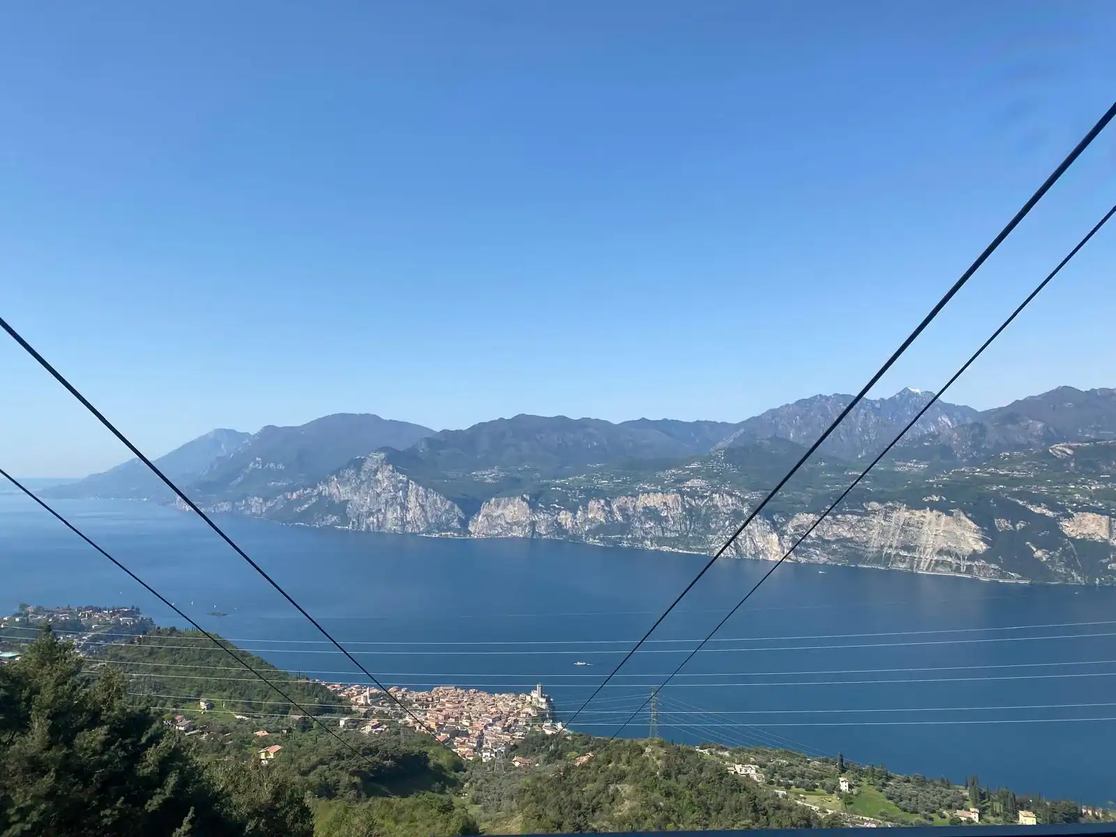 Breathtaking View Of Lake Garda Surrounded By Mountains, With Cable Car Wires In The Foreground, Showcasing Natural Beauty And Travel Destinations In Italy.